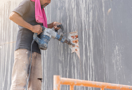 Worker construction destroying. worker with hammer breaking interior wall plasteringの写真素材