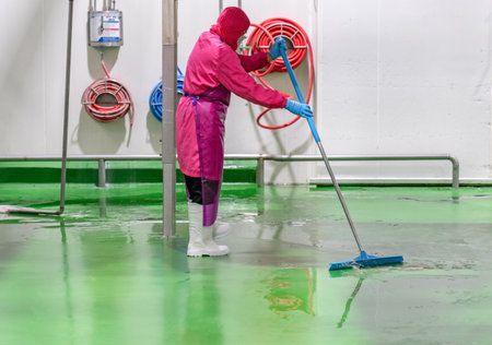 Staff hygien cleaner in protective uniform cleaning floor of food processing plant. Cleaning services.の写真素材