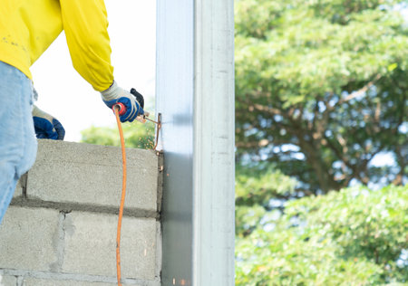 Construction workers welding rebar to steel pole columns to stabilize the masonry to increase the...