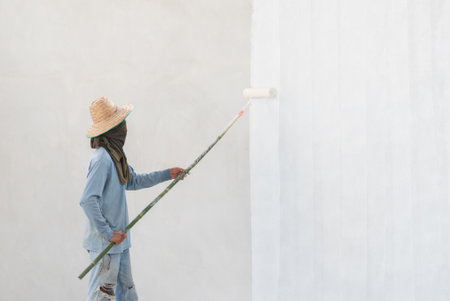 Worker painting wall with paint roller. Painting apartment, renovating with white color paintの写真素材