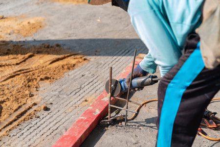 Worker cutting reinforcement with hand tools at a construction site.の写真素材