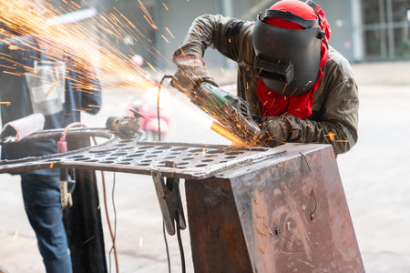 Worker  using electric grinding steel with sparks in an industrial plant.