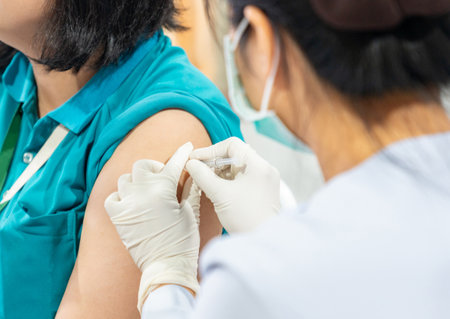 Nurse giving a vaccination shot to a woman patient in hospital.の写真素材