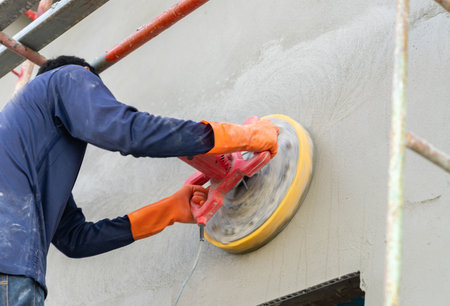 Worker use electric polishing machine mortar on wall in construction site.の写真素材