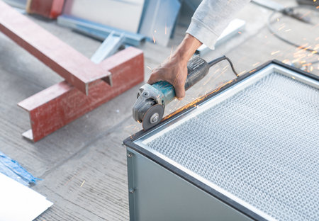 Worker use a grinder to cut the edges of the air filter metal box and spark in workshop