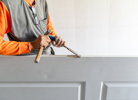 Carpenter working using a chisel with hole wooden door on installing doors hinge.