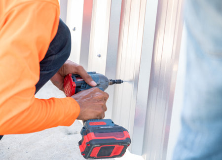 Construction worker install new wall with Metal Sheet. Cordless tool.の写真素材
