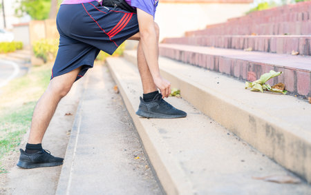 Runner Tie shoelaces on stairs in park.