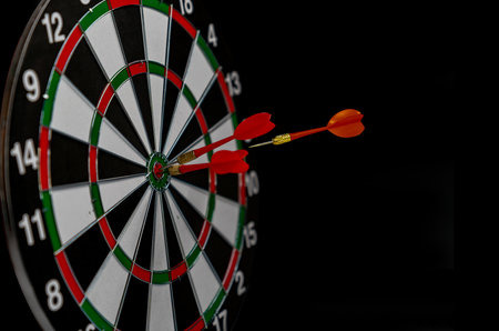 Close up shot red darts arrows in the target center on dark background.