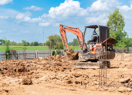 A mini excavator is digging soil at the foundation work area on the construction site.
