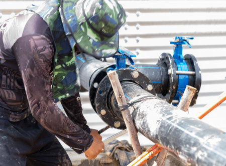 Flange bolts on the water pipeline are being tightened by workers.