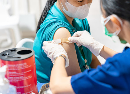 administering a vaccine to a patient while applying a plaster bandage to cover the injection site.