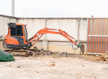 Industrial equipment with an orange body and long arm operating against a background of concrete...