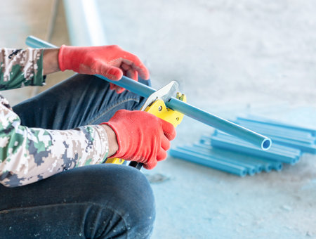 Close-up of Plumber Cutting Blue Plastic Water Pipe with Professional pliers Pipe Cuttersの写真素材