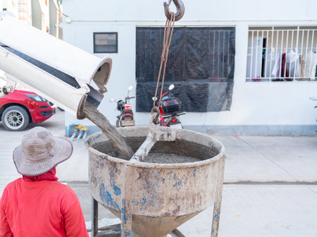 A complete construction sequence showing a cement mixer truck loading wet concrete into a crane-suspended bucket, which is then manually guided by workers to pour the foundation into steel formwork at a building site.の写真素材