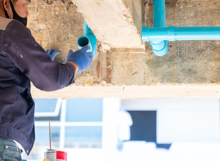 Professional Plumber Installing White PVC Drain Pipe Under Kitchen Sink in new building.の写真素材