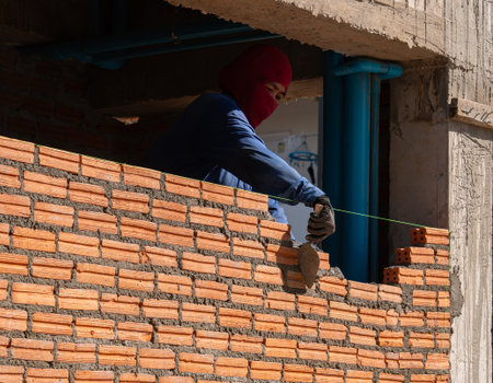Close-up of professional mason building a natural stone wall with mortar at new building.の写真素材