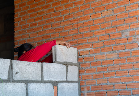 Professional bricklayer building a brick wall with mortar and trowel, focusing on precision masonry construction at a residential building site.の写真素材