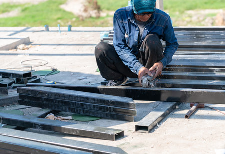 Construction worker using an angle grinder to cut steel beams with spark on-site.の写真素材