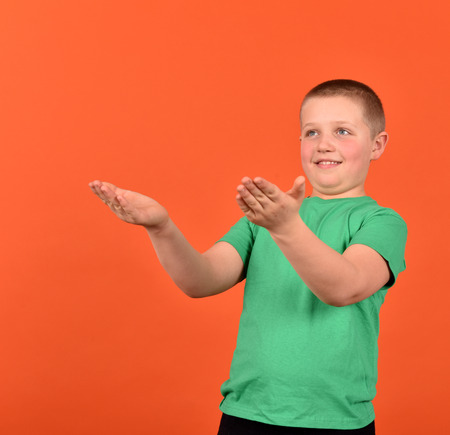 The boy stretches his hands. A good mood. The boy is on an orange background.の写真素材