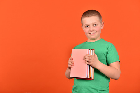 A boy with books. Positive mood. A young man on an orange background.