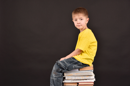 A boy with books. A schoolboy teaches lessons. Shooting in a studio. A child in a yellow T-shirt. A smart person. A commitment to knowledge.の写真素材