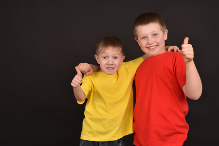 Two boys on a black background. Children in T-shirts. Good mood. Happy childhood. A strong friendship.の写真素材