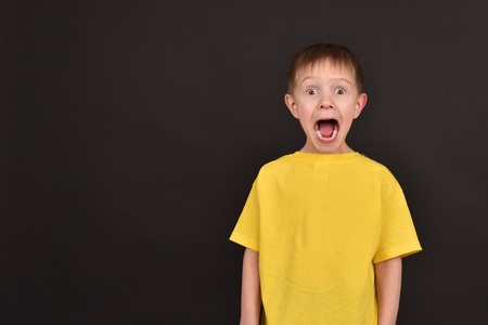 Emotional guy. Portrait of a boy in a T-shirt. Shooting in the studio. A young man on a black background.の写真素材