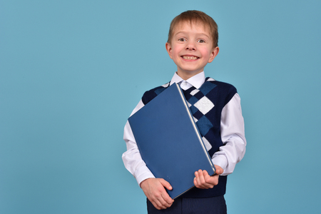 A cheerful teenager on a blue background. Schoolboy with a book. Striving for knowledge.の写真素材