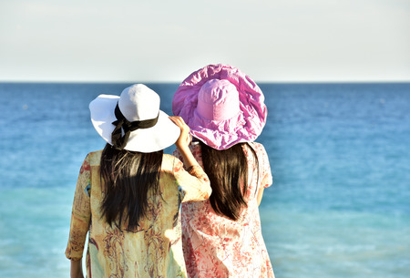 Two girls are looking towards the sea. Summer holidays. A good rest.の写真素材