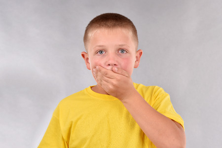 The boy covered his mouth with his palm.の写真素材