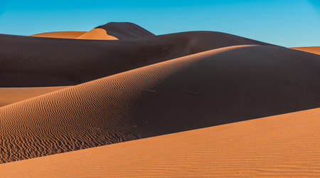 Orange sand dunes in Erg Chigaga with shadows and blue sky, Moroccoの写真素材