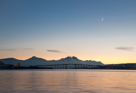Panoramic view of arctic town Tromso during beautiful dusk with mountains and horned moon backgroundの写真素材