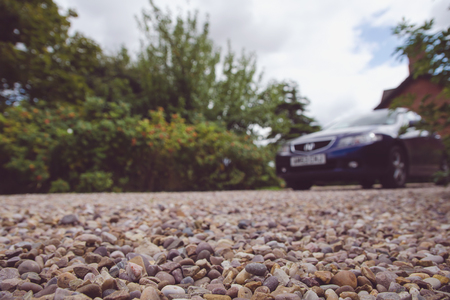 Car parked in front of the house. Focus on a little pebbles close to the camera.の写真素材