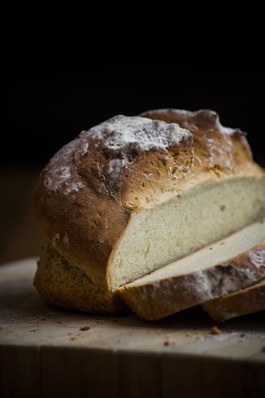 Soda bread on a wooden board with dark background.