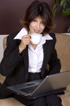 formal business woman with laptop holding coffee cupの写真素材