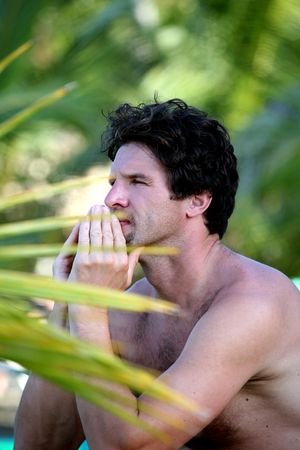 attractive man sitting on the beach under palm treesの写真素材