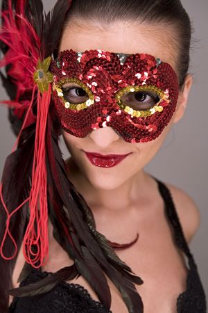mysterious brunette wearing carnival red mask on her faceの写真素材