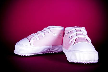 pair of pink baby shoes on dark backgroundの写真素材