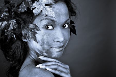 pretty brunette woman wearing leaves and colorful makeupの写真素材
