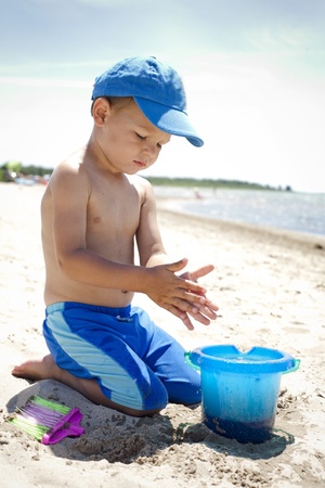 boy toddler is playing with sand on the beach の写真素材