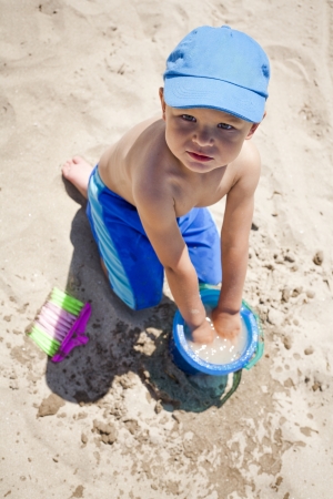 boy toddler is playing with sand on the beach の写真素材