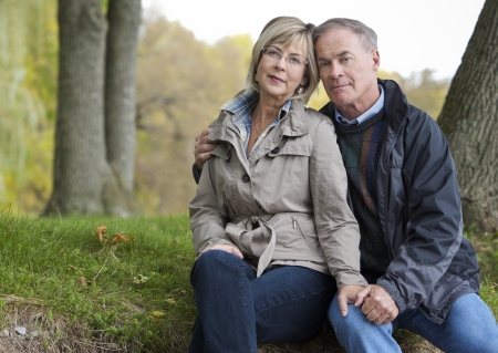 older casual couple sitting in the grass outdoorsの写真素材