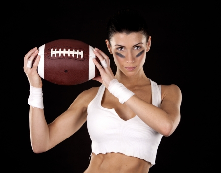 athletic brunette posing as american football girl on black backgroundの写真素材