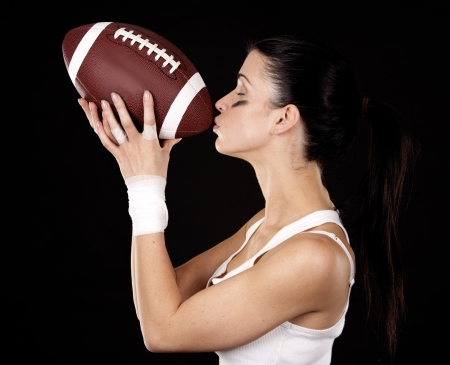 athletic brunette posing as american football girl on black backgroundの写真素材