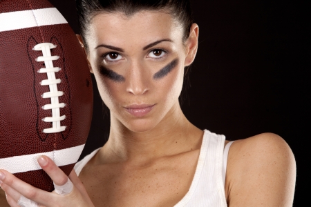 athletic brunette posing as american football girl on black backgroundの写真素材