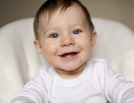 happy baby sitting in her chair wearing white