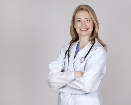 blond female doctor posing on light grey backgroundの写真素材