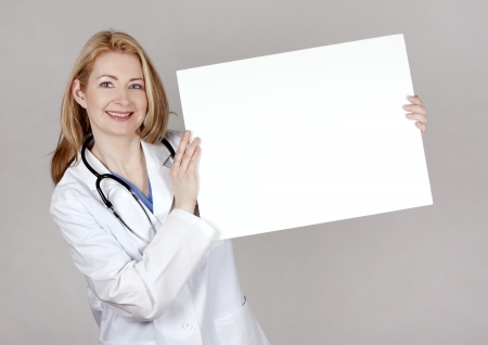 blond female doctor posing on light grey backgroundの写真素材