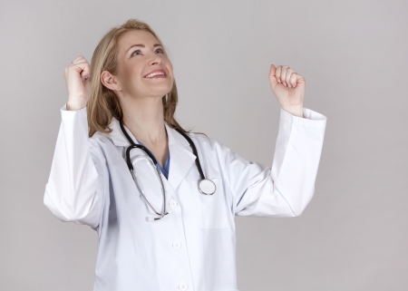 blond female doctor very happy on grey backgroundの写真素材